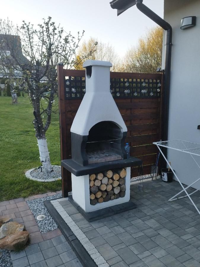 Murowany grill na drewno przy domu, obok drzewko z lampkami